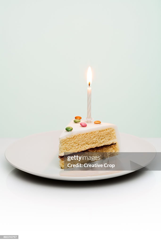 Slice of birthday cake with candle sticking out of