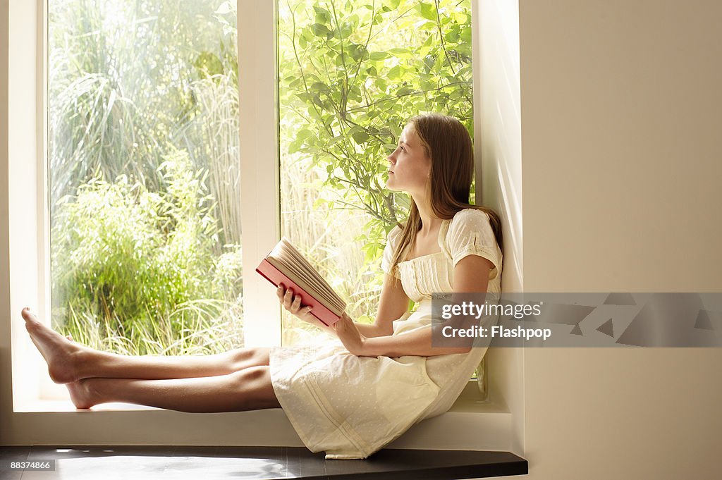 Portrait of girl daydreaming, holding a book