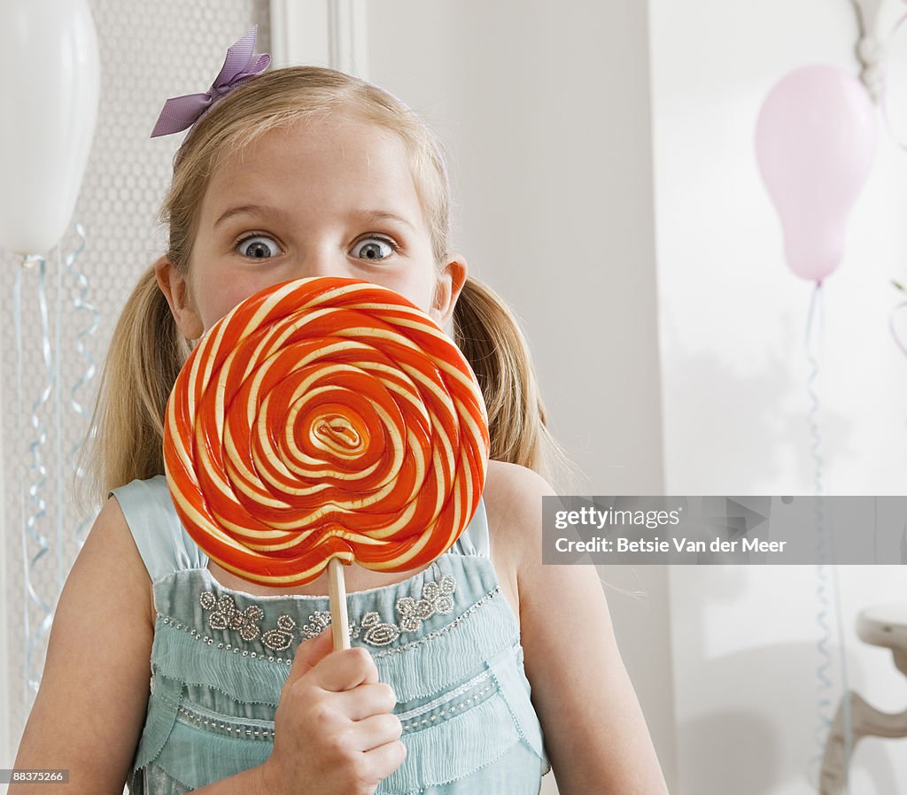 Girl holding large lollipop.