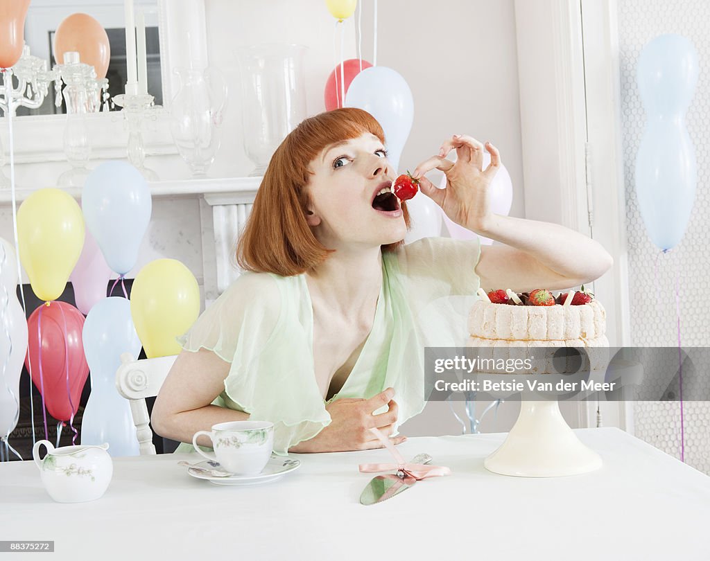 Woman nibbling from large cake.