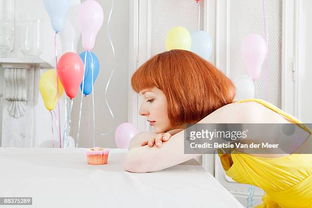 woman looking at cupcake. - temptation stock-fotos und bilder