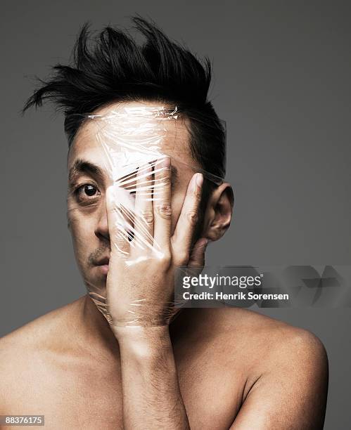 young man with hand  front of his eye wrapped up w - man wrapped in plastic stock pictures, royalty-free photos & images