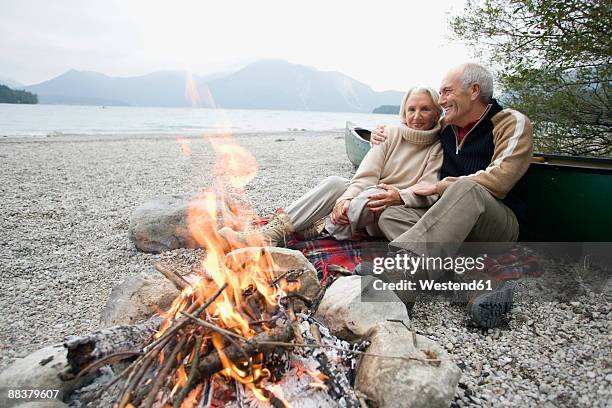 germany, bavaria, senior couple sitting at campfire - mountian fire fotografías e imágenes de stock