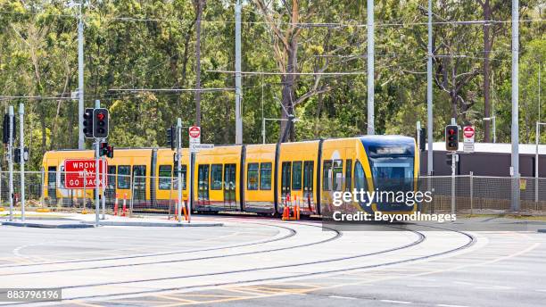 new g:link light rail vehicle turns at main road intersection - gold coast light rail stock pictures, royalty-free photos & images