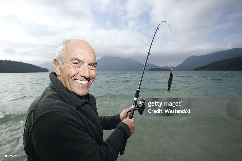 Germany, Bavaria, Walchensee, Senior man fishing in lake