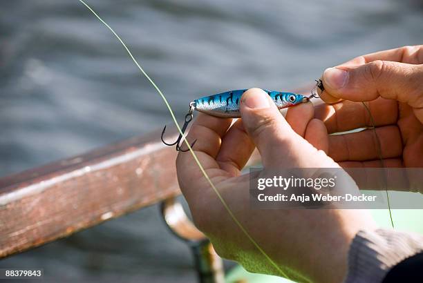 man's hand fixing bait on hook, elevated view - vishaak visgerei stockfoto's en -beelden