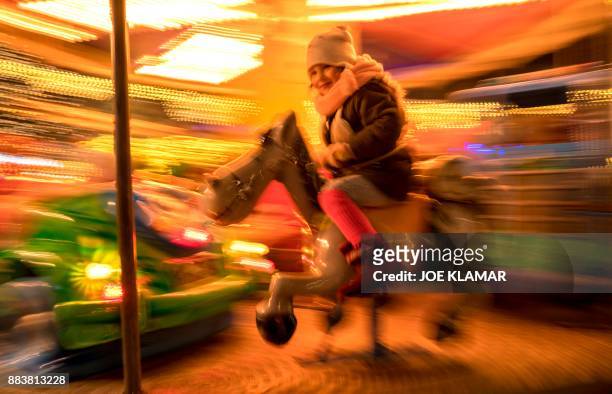 Girl takes a carousel ride at the Christmas market in Sankt Poelten, Austria on December 01, 2017. / AFP PHOTO / JOE KLAMAR