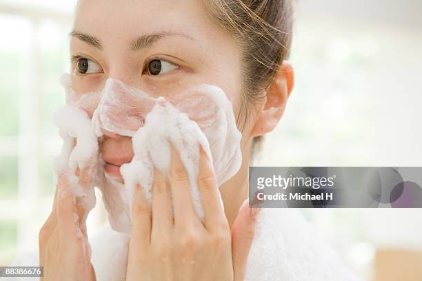 the woman is washing her face.  - woman face cleaning photos et images de collection