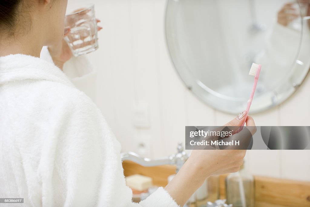 The woman brushes her teeth. 