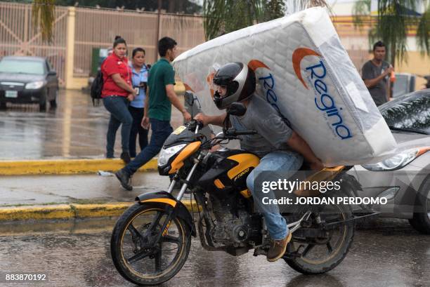 Man carries a matress looted from a shop as supporters of Honduran presidential candidate for the Opposition Alliance against the Dictatorship...