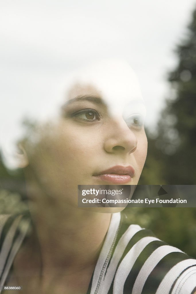 Young woman looking through window