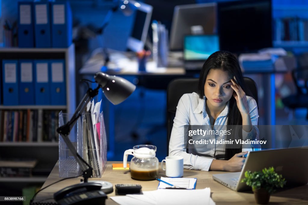 Worried young woman working at late