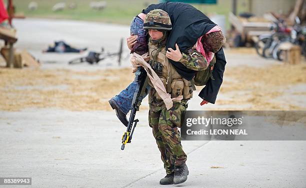 British First Infantry soldier carries a "blast victim" in a training exercise at a new "Afghan village" at a military base in Norfolk, in eastern...