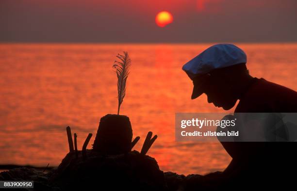 A young boy building a sandcastle at sunset