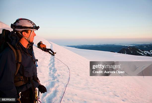 a climber enjoys the sunrise over a field of crevasses on mt. olympus. - mount-olympus-olympic-national-park stock pictures, royalty-free photos & images