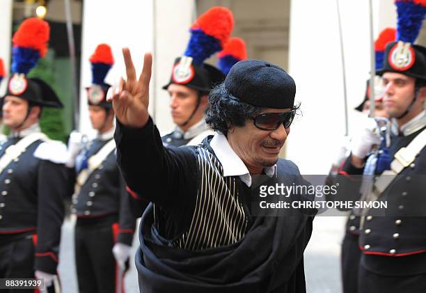 Libya's leader Moamer Kadhafi flashes a V-sign as he is greeted by Italian Prime Minister Silvio Berlusconi prior their meeting on June 10, 2009 at...