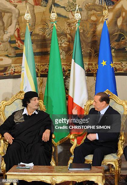 Libya's leader Moamer Kadhafi listens to Italian Prime Minister Silvio Berlusconi during their meeting on June 10, 2009 at the Palazzo Chigi in Rome....