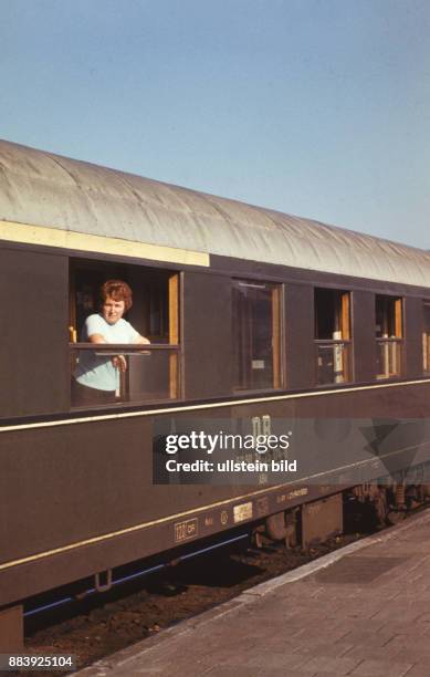 Frau im Zug der Deutschen Reichsbahn am Bahnhof