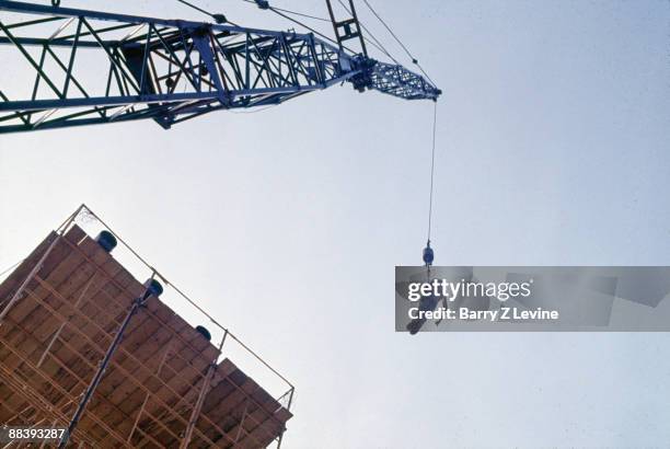 An unidentified man in a harness flashes a 'thumbs up' sign as he is lifted via crane to the top of a lighting tower at the Woodstock Music and Arts...