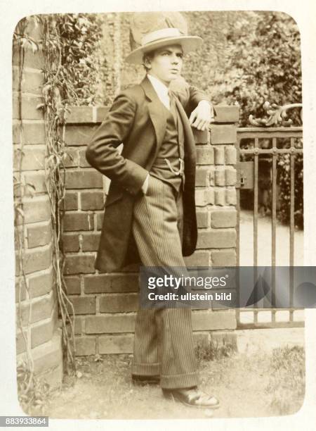 Aufnahme ca. 1910, Junger Mann im Anzug an der Gartenmauer