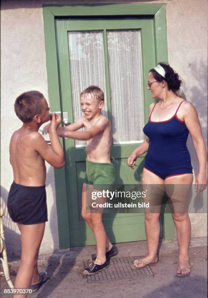 Ca. 1950, Kindheit, zwei Jungen und eine Frau in Badekleidung vor einer Tür