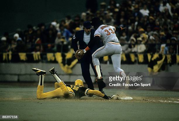 Outfielder Omar Moreno of the Pittsburgh Pirates dives back into first base safe while first baseman Eddie Murray of the Baltimore Orioles leaps over...