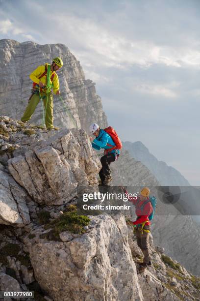 wandelaars op een rots berg klimmen - berg klimmen team stockfoto's en -beelden
