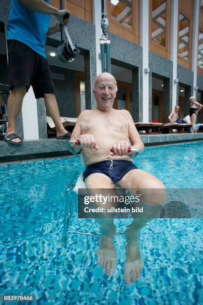 Bad Saarow Therme Symbolbild / Senior im Schwimmbad in Bad Saarow, Thermalsolewasser der Catharinenquelle beim baden , Mann wird mit Behindertenlift...