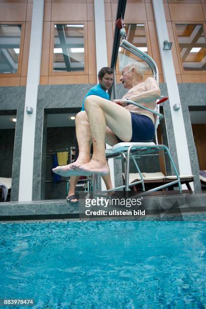 Bad Saarow Therme Symbolbild / Senior im Schwimmbad in Bad Saarow, Thermalsolewasser der Catharinenquelle beim baden , Mann wird mit Behindertenlift...