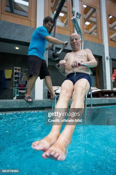 Bad Saarow Therme Symbolbild / Senior im Schwimmbad in Bad Saarow, Thermalsolewasser der Catharinenquelle beim baden , Mann wird mit Behindertenlift...