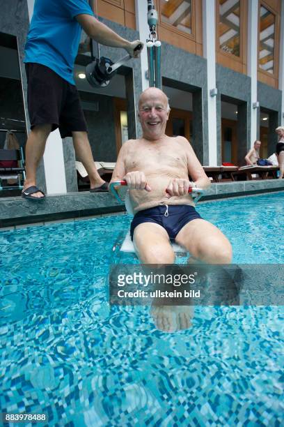 Bad Saarow Therme Symbolbild / Senior im Schwimmbad in Bad Saarow, Thermalsolewasser der Catharinenquelle beim baden , Mann wird mit Behindertenlift...