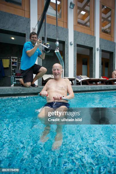 Bad Saarow Therme Symbolbild / Senior im Schwimmbad in Bad Saarow, Thermalsolewasser der Catharinenquelle beim baden , Mann wird mit Behindertenlift...