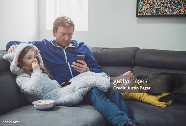 father and daughter relaxing on the sofa - één ouder stockfoto's en -beelden
