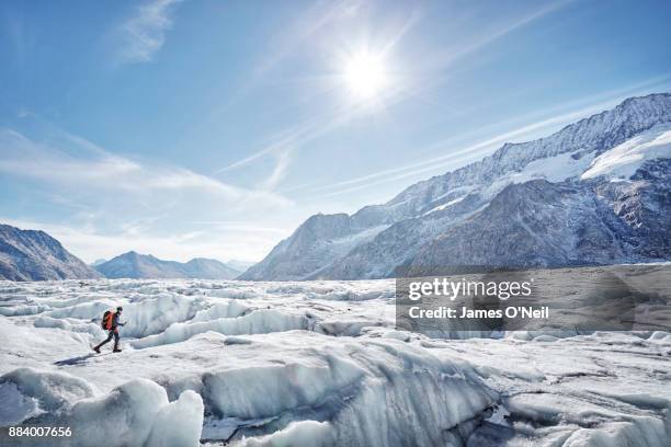 hiker on glacier with distant mountains, aletsch glacier, switzerland - gletsjer stockfoto's en -beelden