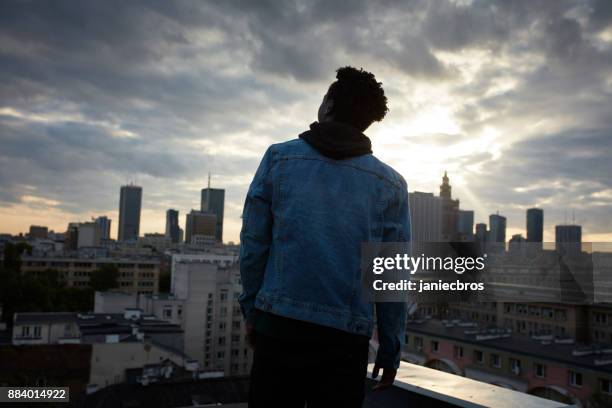 一個年輕的非洲男子的肖像。背景中的城市天際線 - denim jacket 個照片及圖片檔