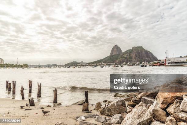 view on sugar loaf mountain in bay of rio de janeiro under grey sky - rio ave stock pictures, royalty-free photos & images