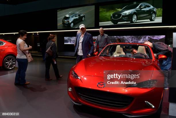 People inspect the 2018 Mazda MX-5 Miata on display at the Los Angeles Auto Show in the Los Angeles Convention Center in Los Angeles, California on...