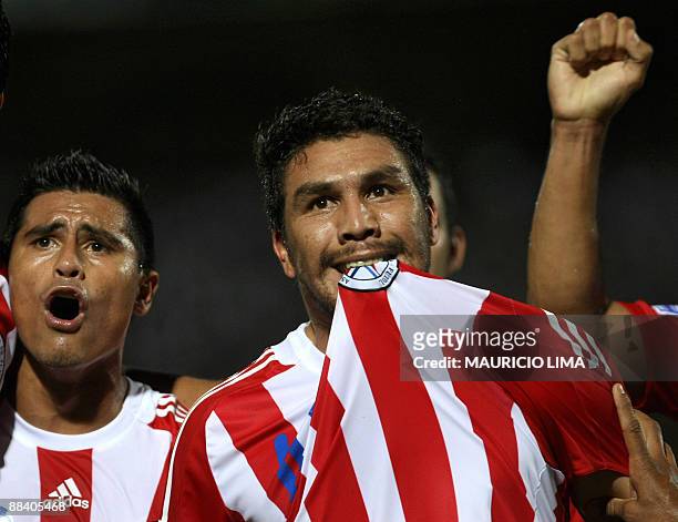 Paraguay's Salvador Cabanas bites his jersey while he celebrates his goal with teammate Osvaldo Martinez during their FIFA World Cup South...