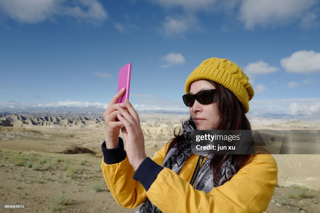 A young woman USES electronic equipment to make beautiful highland scenery in ali, Tibet