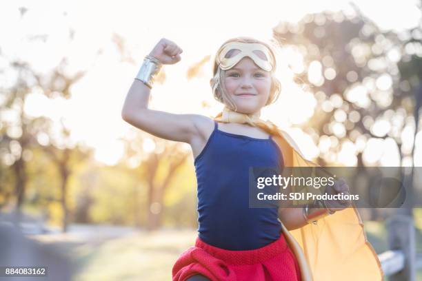 little girl pretends to be strong superhero - coragem imagens e fotografias de stock