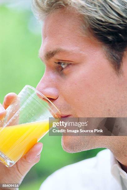 man drinking orange juice - mangiare fotografías e imágenes de stock
