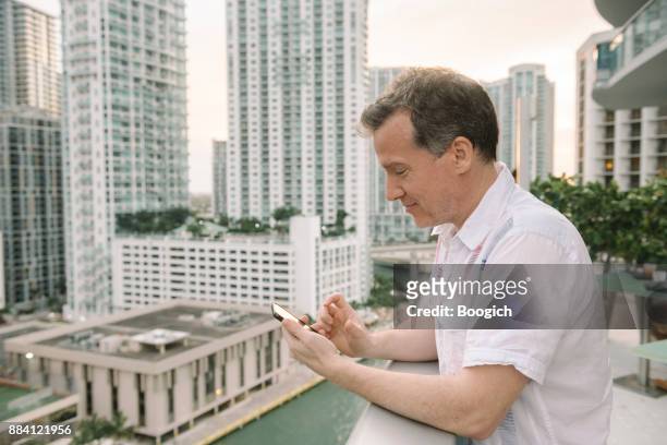 mature man texting with view of downtown miami brickell buildings - miami river florida stock pictures, royalty-free photos & images