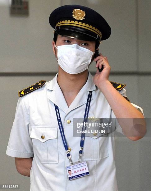 Masked chinese airport security employee talks on his mobile phone at Beijing International Airport on June 11, 2009. Chinese authorities have...