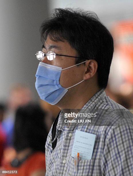 Masked passenger stands in the terminal hall at Beijing International Airport on June 11, 2009. Chinese authorities have submitted passengers to...