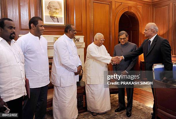 Tamil National Alliance delegation Leader R. Sambanthan shakes hands with Indian Foreign Secretary Shiv Shankar Menon during a meeting with Indian...