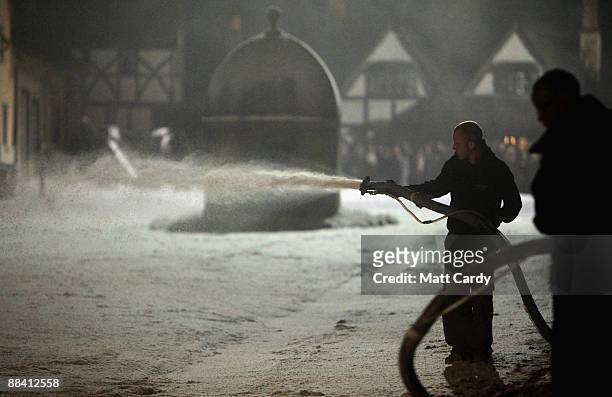 Man sprays false snow in the front of buildings that have been transformed for a night shoot of the BBC period drama, Cranford, on June 10, 2009 in...