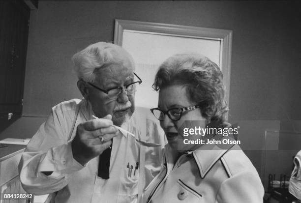 Colonel Harland David Sanders and his wife Claudia in their kitchen. Hartland gives Claudia a taste of the cooking. Colonel Sanders founded...