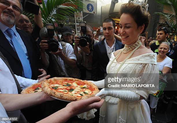 An actress dressed like Queen Margherita of Savoy is presented a pizza named after her during a ceremony to celebrate the 120th anniversary of the...