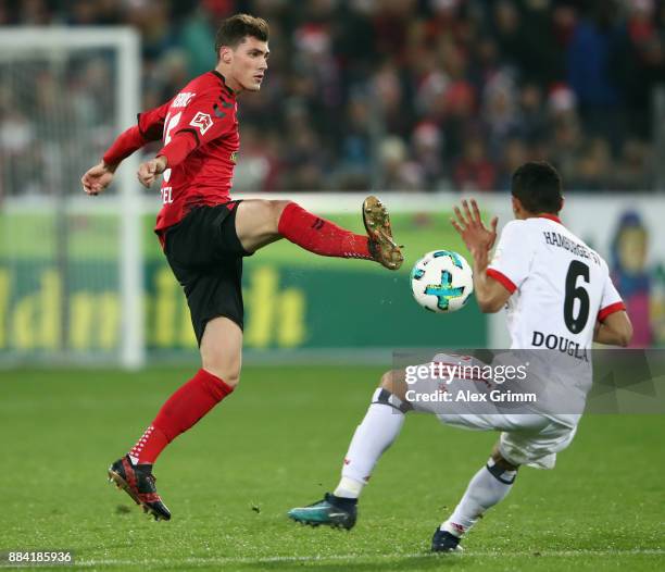 Pascal Stenzel of Freiburg is challenged by Douglas Santos of Hamburg during the Bundesliga match between Sport-Club Freiburg and Hamburger SV at...