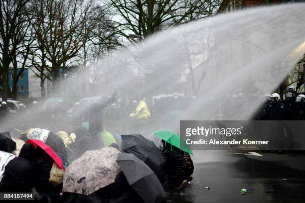 Left-wing protesters get sprayed by a water cannon as they clash with police forces outside the Hannover Congress Centrum prior to today's AfD...